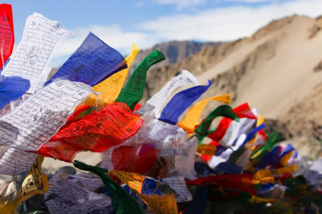 blue, white, red, green, and yellow prayer flags fluttering in the wind create a beautiful and peaceful scene